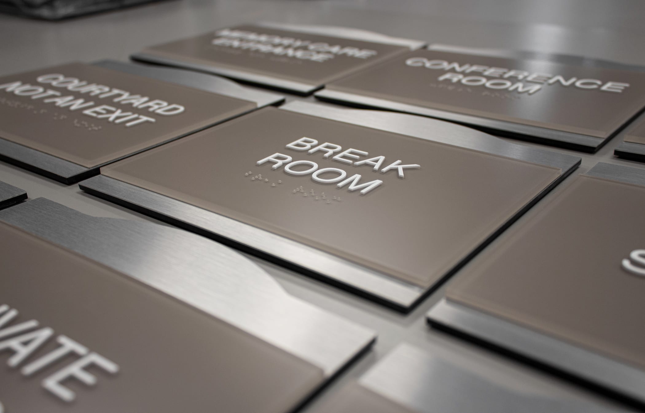 ADA Compliant signage features raised lettering and braille to comply with the Americans with Disabilities Act