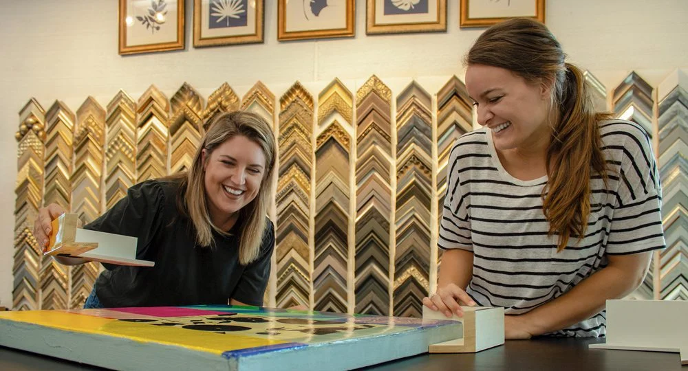 Senior art consultants review frame options for custom canvas art.
