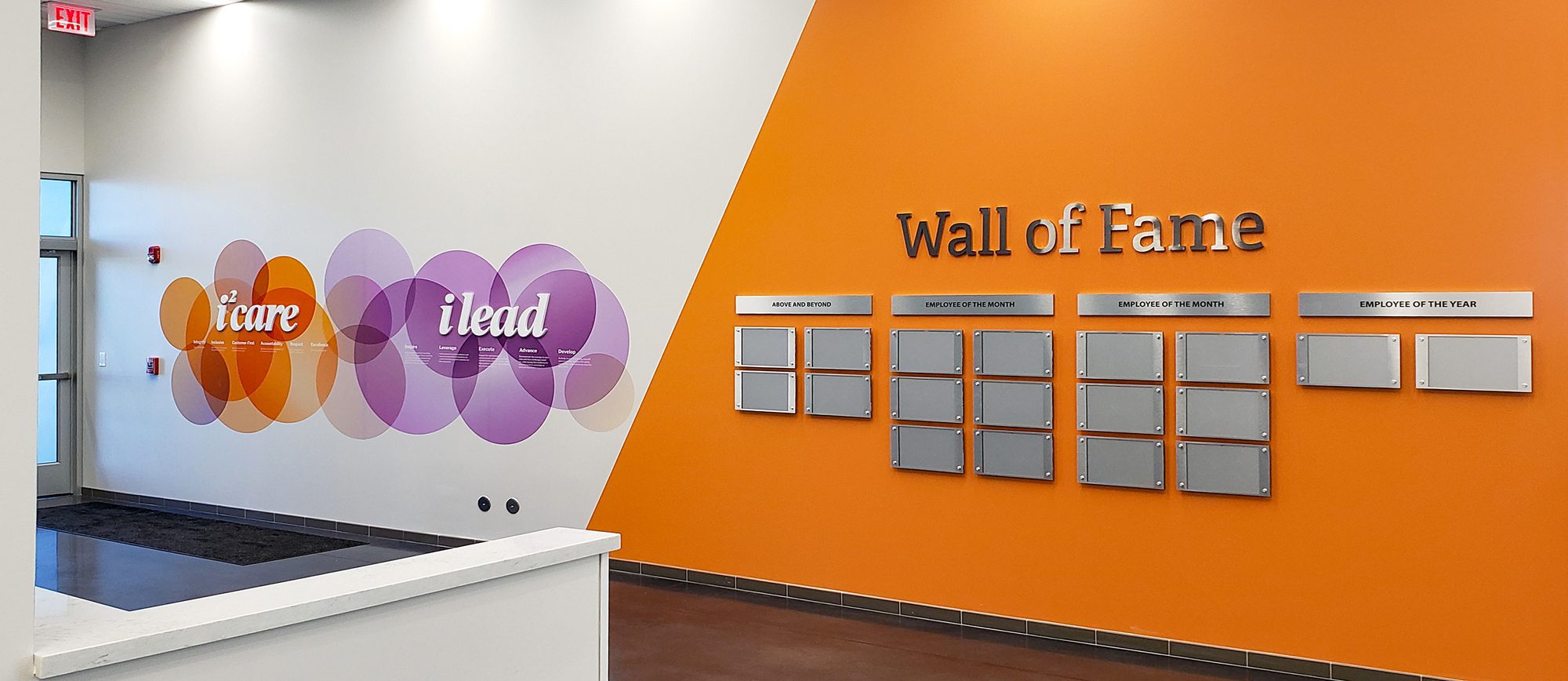 Branded wall graphics and an employee recognition wall at a company headquarters.
