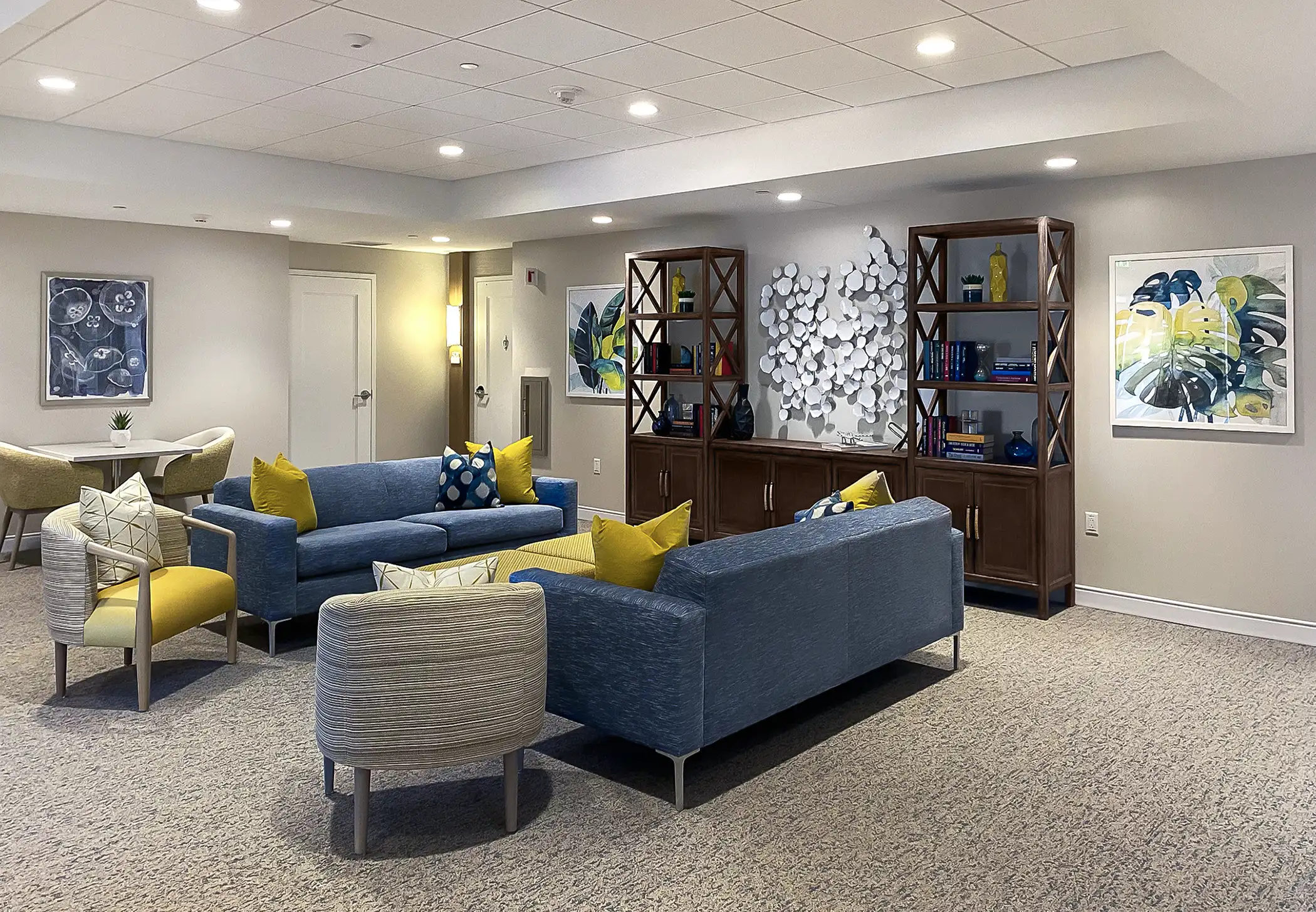 Assisted living common area features dimensional wall decor and framed artwork in a luxury setting.