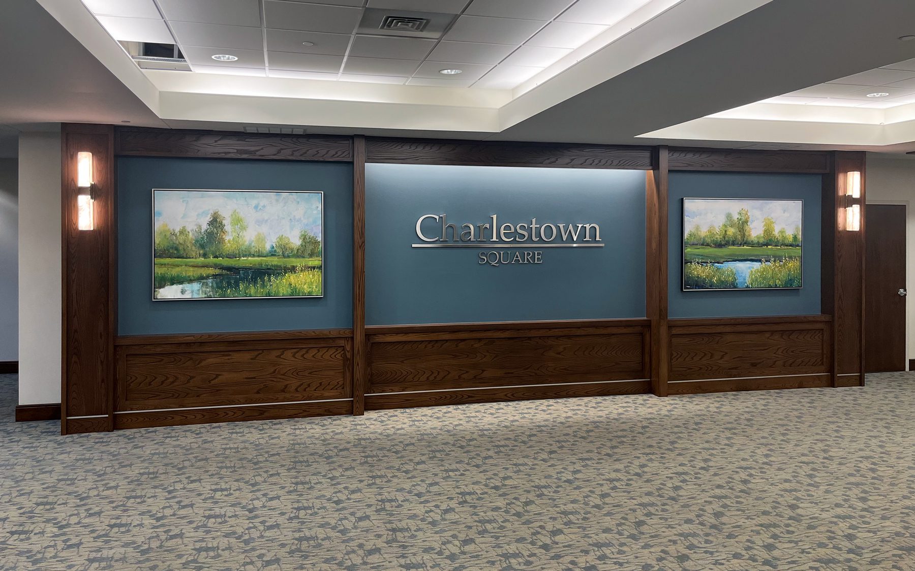 A dimensional logo sign paired with oversized canvas artwork creates an attractive entryway at a senior living community.