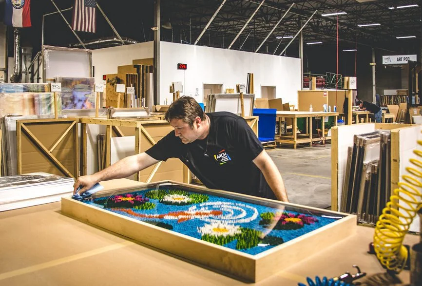 A framing specialist performs a quality inspection of shadowbox artwork prior to delivery and installation.