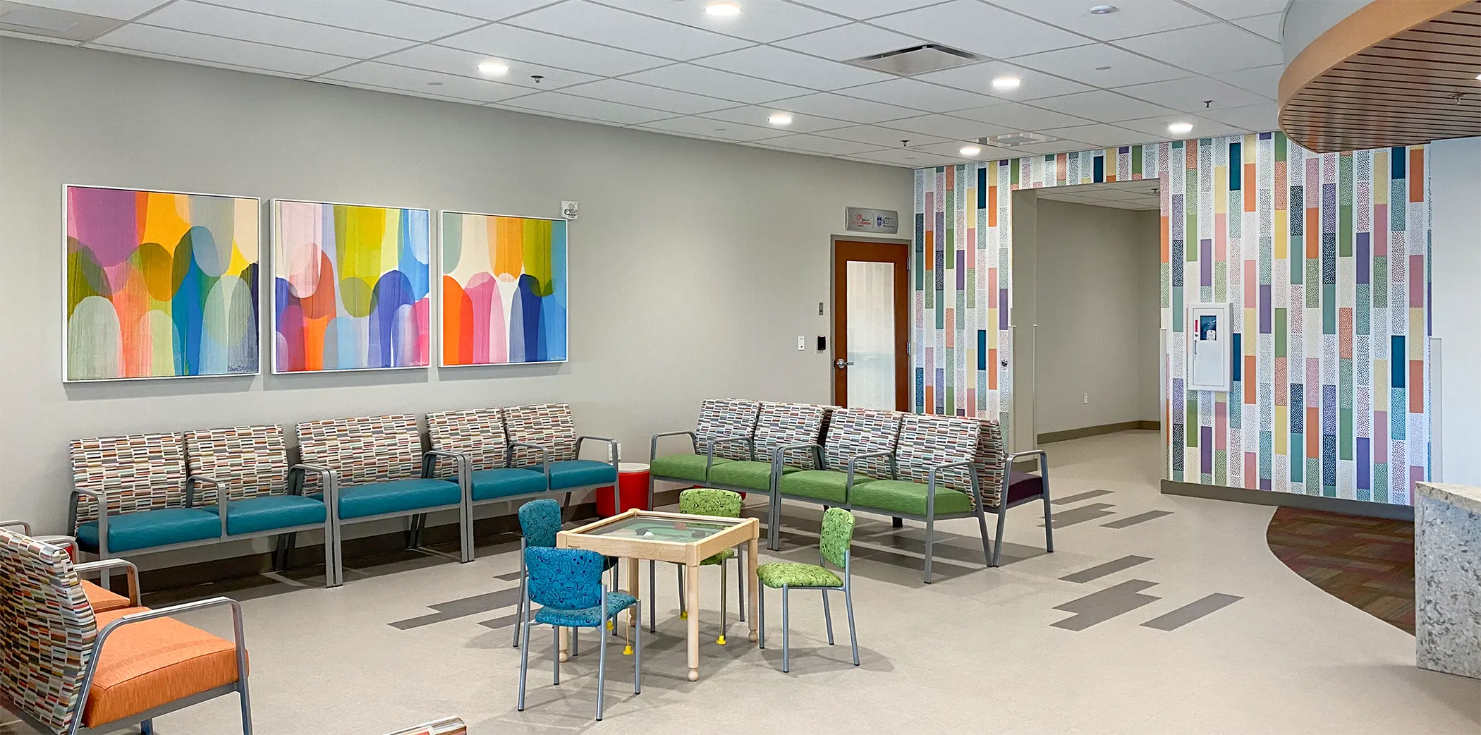 A custom wall graphic and colorful canvas art add to the family-friendly design of this healthcare lobby.